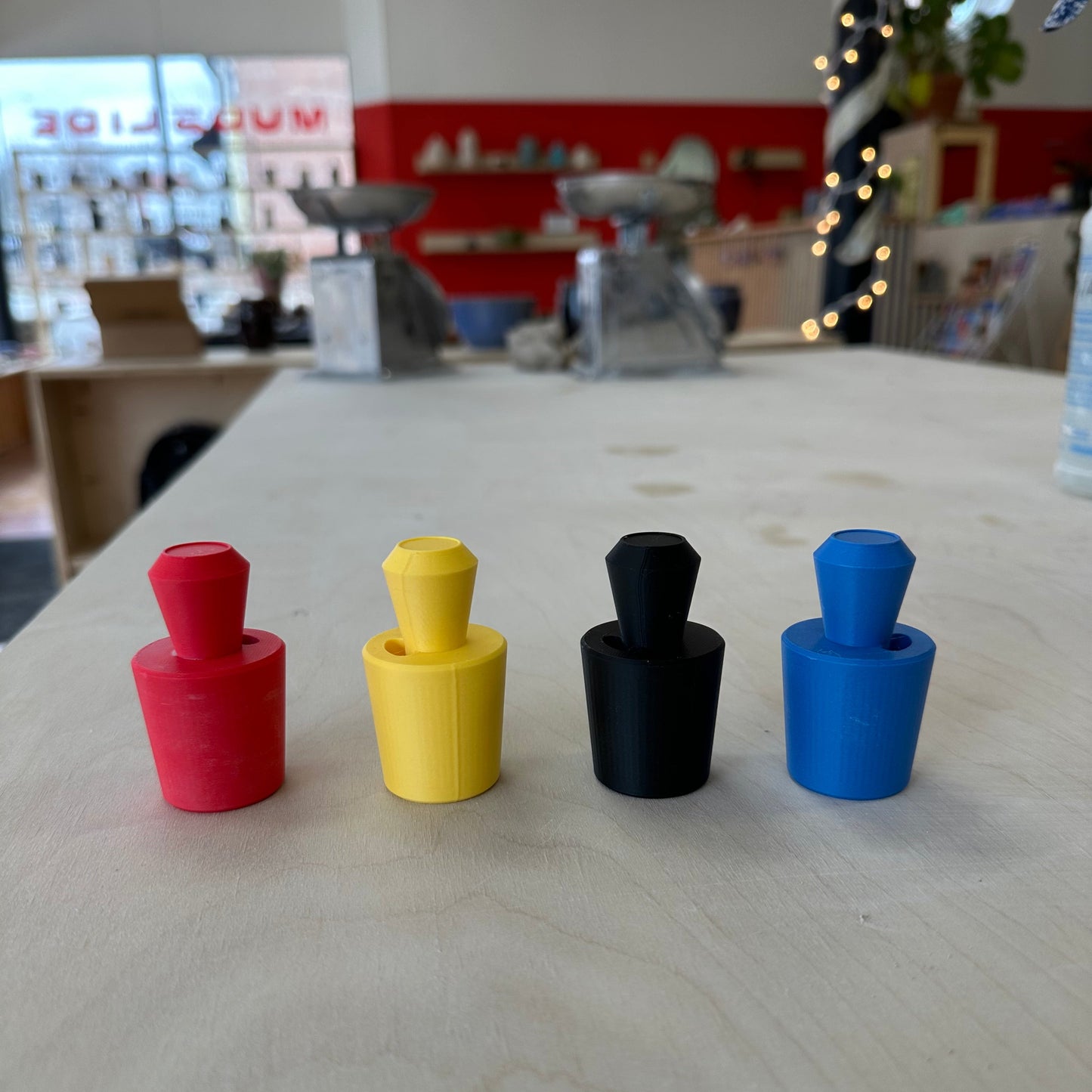 four cork sizer tools on a table in red, yellow, black, and blue