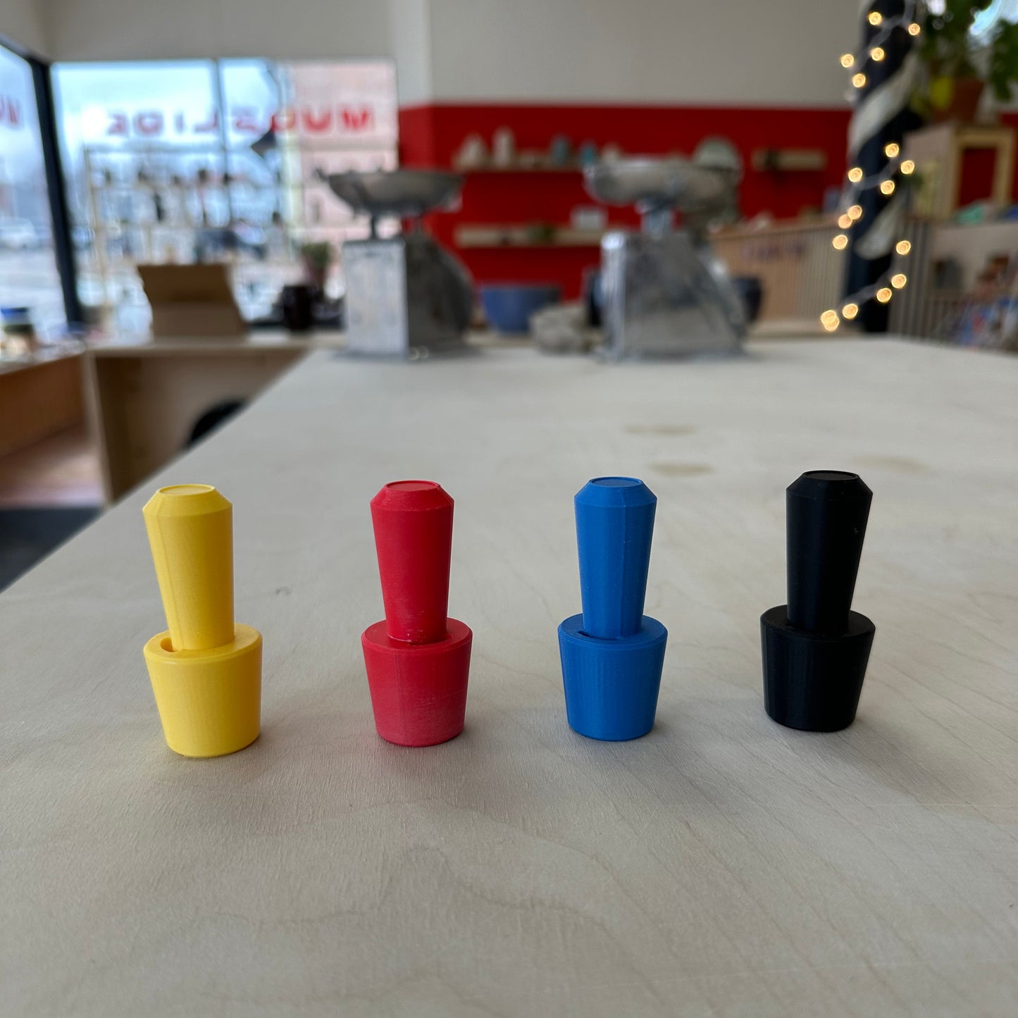 four plastic oil sizers on a table, yellow, red, blue, and black