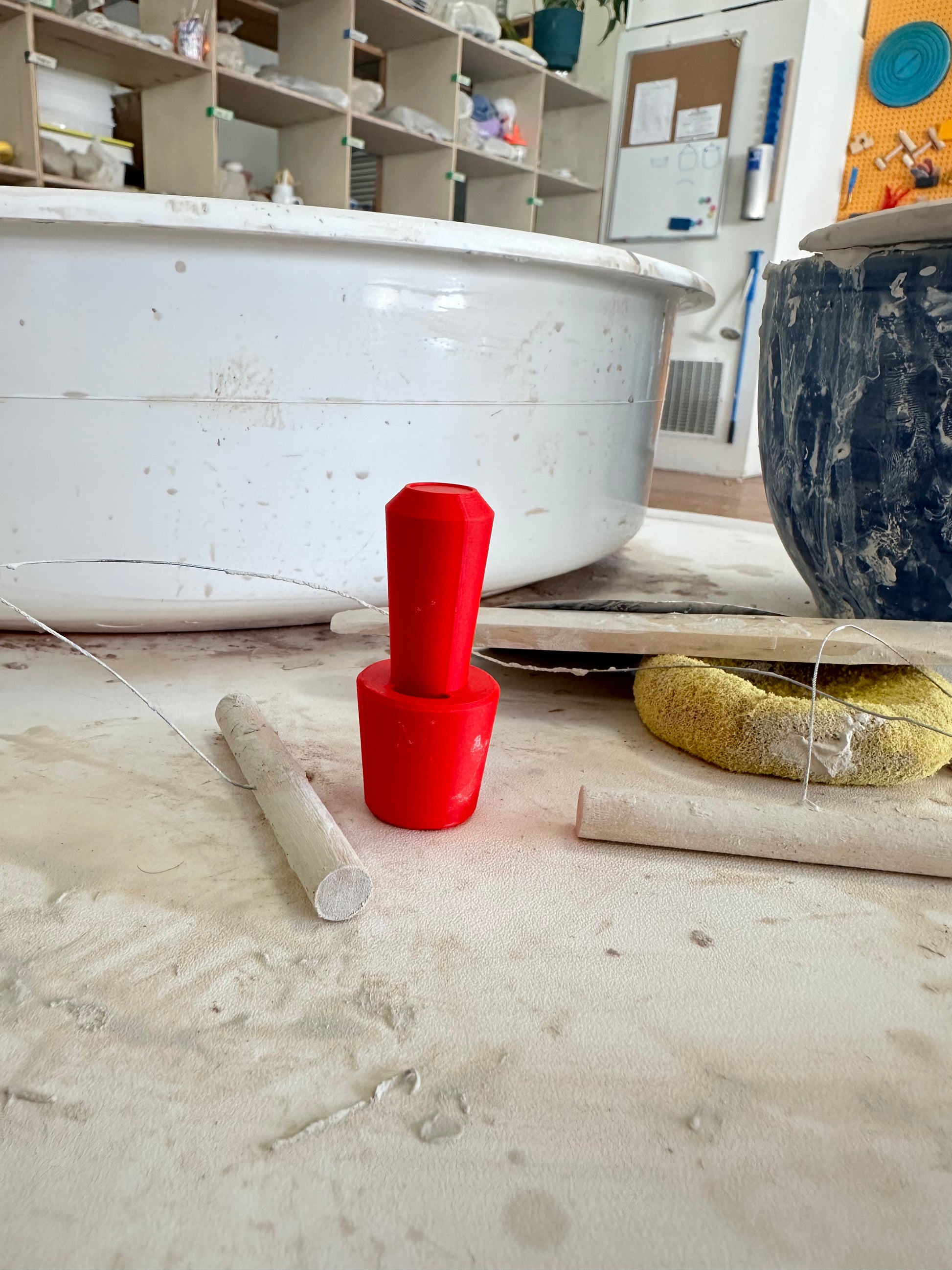 red plastic oil sizer tool on a pottery wheel